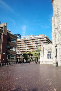 Şehir meydanında bir saat kulesi ve arka planda bir bina.