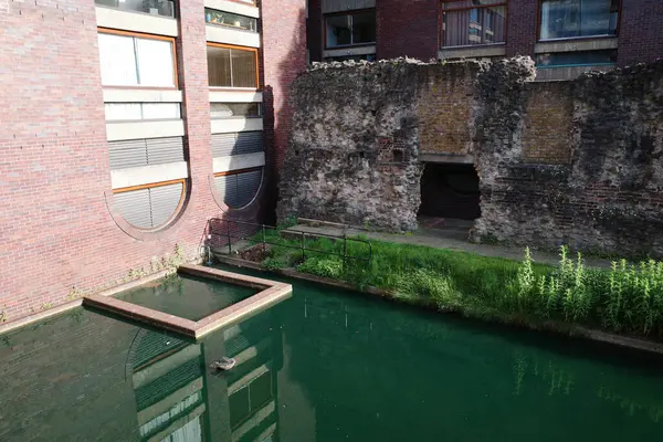 Önünde havuz olan tuğla bir bina.