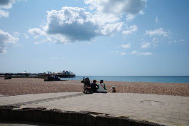 Sahilde bir bankta oturan iki kişi.