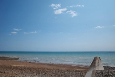 Sudan sarkan büyük bir kayanın olduğu bir sahil.