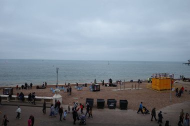 Okyanusun kıyısındaki sahilde yürüyen bir kalabalık.