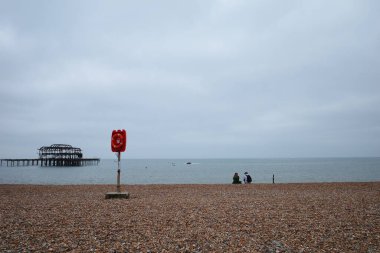 Okyanusun kıyısında sahilde oturan bir çift.