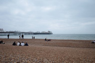İnsanlar okyanus kıyısında bir sahilde oturuyorlar.
