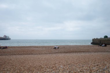 Sahilde oturan ve arka planda teknesi olan insanlar.