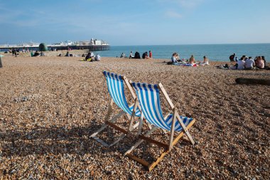 Bir çakıl taşlı plajda iki plaj sandalyesi