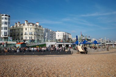 Kumsalda insanların oturduğu bir kumsal ve şemsiyeler.