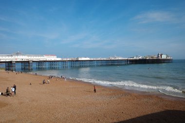Üzerinde insanlar olan bir sahil ve arka planda bir rıhtım.