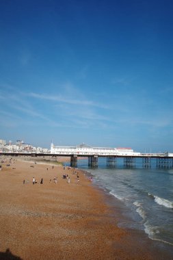 Üzerinde insanlar olan bir sahil ve arka planda bir rıhtım.