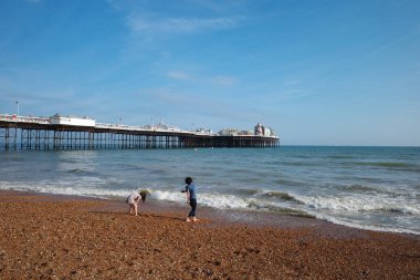 Okyanus kıyısındaki bir sahilde yürüyen iki kişi.