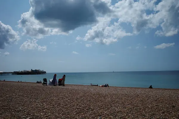 İnsanlar mavi gökyüzü olan bir plajda oturuyor.