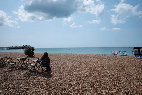 Okyanus manzaralı bir sahilde oturan bir kadın.