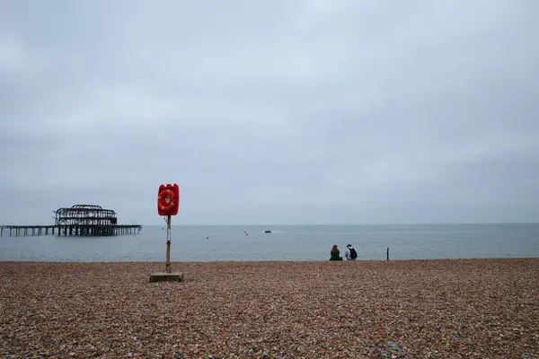 Okyanusun kıyısında sahilde oturan bir çift.