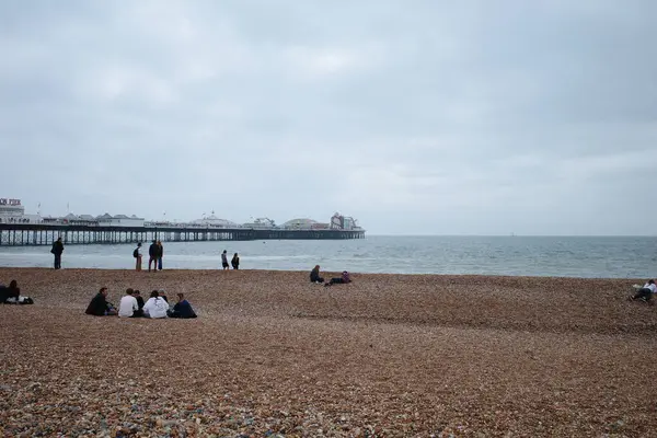 İnsanlar okyanus kıyısında bir sahilde oturuyorlar.