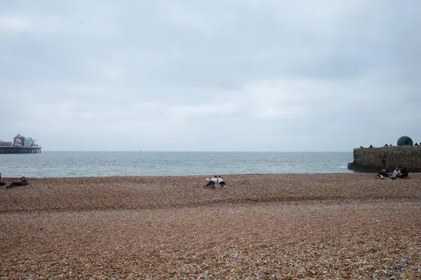 Sahilde oturan ve arka planda teknesi olan insanlar.