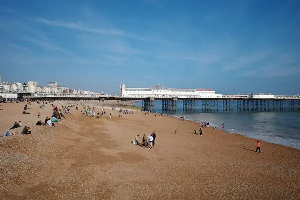Üzerinde insanlar olan bir sahil ve arka planda bir rıhtım.