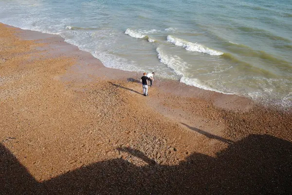 Sahilde sörf tahtasıyla yürüyen biri.