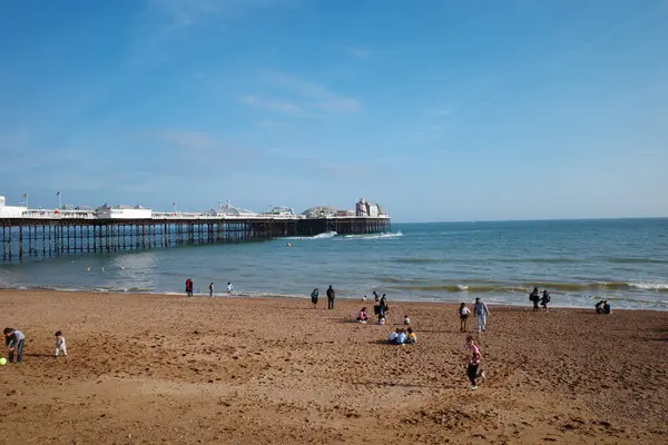 Üzerinde insanlar olan bir sahil ve arka planda bir rıhtım.