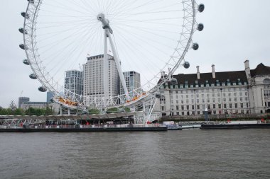 Arka planda bir şehir olan bir nehirde dönme dolap.