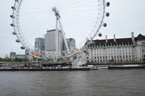 Arka planda bir şehir olan bir nehirde dönme dolap.