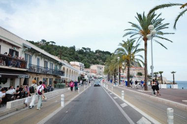 Palmiye ağaçları ve kaldırımda yürüyen insanlarla dolu bir cadde.