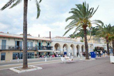 Palmiye ağaçları ve yürüyen insanlarla dolu bir sokak.