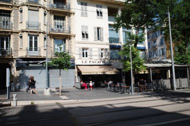 Kafesi olan bir sokak köşesi ve masalarda oturan insanlar.