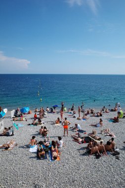 Kumsalda uzanan insanlar ve mavi bir gökyüzü.