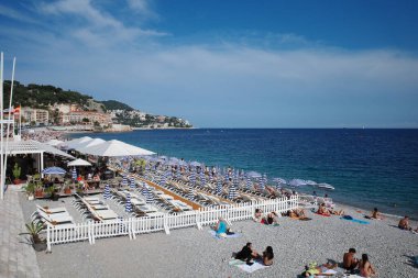 Kumsalda bir sürü insan oturuyor.