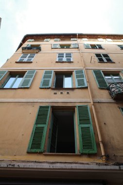 Yeşil panjurları ve balkonu olan yüksek bir bina.