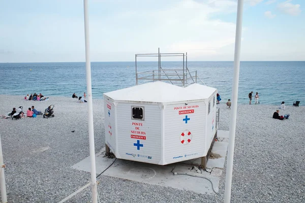 Kumsalda bir cankurtaran istasyonu ve kumların üzerinde oturan insanlar.