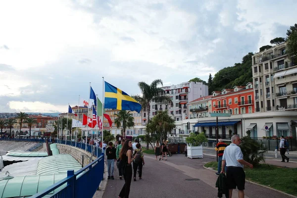 Bir grup insan nehrin kenarındaki kaldırımda yürüyor.