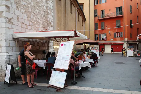 Elinde menüyle masanın önünde duran bir kadın.