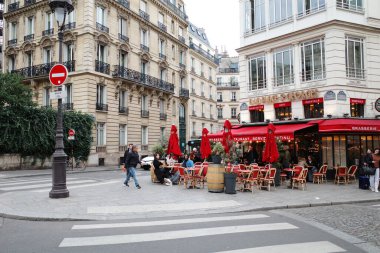 Bir kafe ve birkaç kişinin olduğu bir sokak köşesi.