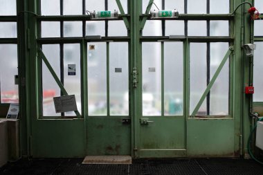 Penceresi ve tabelası olan yeşil bir kapı.