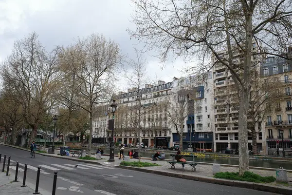 Birkaç kişinin yürüdüğü bir cadde ve birkaç bina.