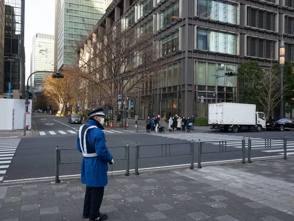 Mavi ceketli bir adam kaldırımda duruyor.