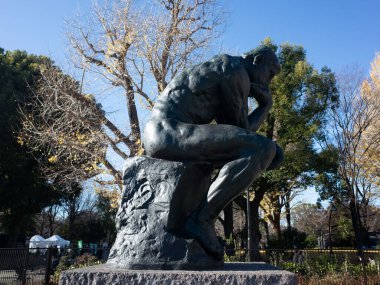 Bir kayanın üzerinde oturan bir adam heykeli.