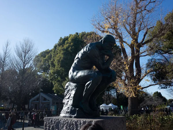 Bir kayanın üzerinde oturan bir adam heykeli.