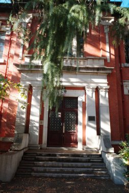 Beyaz kapısı ve ağacı olan kırmızı tuğlalı bir bina.