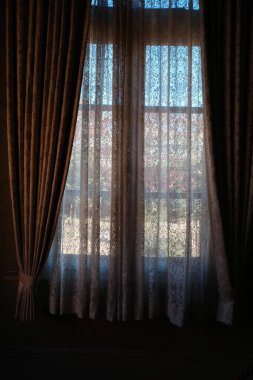 Perdeli bir pencere ve önünde bir sandalye.