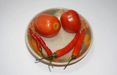 Red tomatoes and chilies in a small bowl.