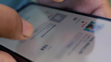 Akıllı telefon kullanan, çeşitli uygulama simgeleri ve uyarıları gösteren ekrana odaklanan bir kişinin yakın plan görüntüsü.
