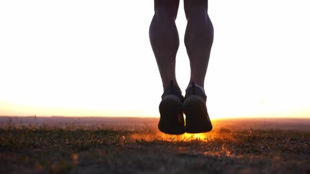 日落时 一个肌肉发达的人跳过田里的绳子 — 图库视频影像