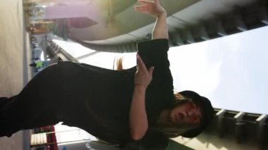 Panama şapkalı gülümseyen kadın köprü altında dans ediyor. Dikey çekim