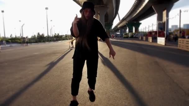 戴着巴拿马帽的年轻女子在明媚的阳光下慢动作地在桥下跳舞 — 图库视频影像