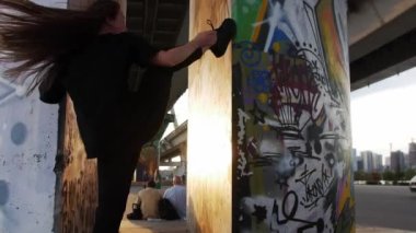 08-13-22 RUSSIA, KAZAN: Grafiti arka planında dans eden güzel uzun düz saçlı genç akrobatik kadın. Orta çekim