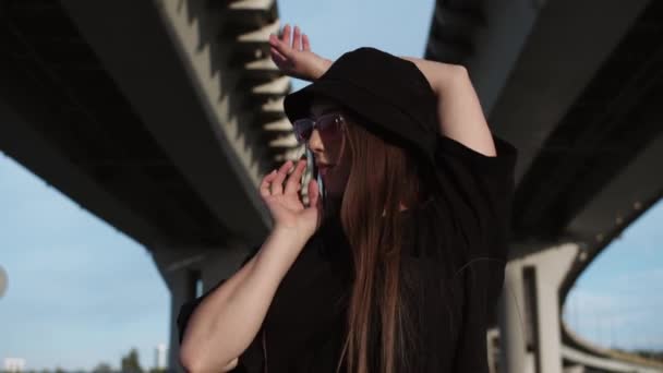 Młoda Kobieta Czarnej Panamie Różowych Okularach Tańcząca Pod Mostem Środek — Wideo stockowe
