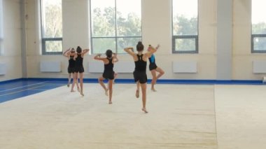 18-08-2022 RUSSIA, KAZAN: Benzer takım elbiseli bir grup kız jimnastikçi spor salonunda gösteri eğitimi veriyor. Orta çekim