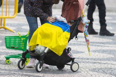 10-29-2022 LISBON, PORTUGAL: Lizbon 'daki Ukrayna protestosu - Ukrayna bayrağı ile kaplı bir bebek arabasında bir çocuk. Orta çekim