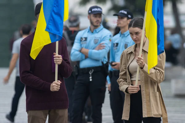 stock image 10-29-2022 LISBON, PORTUGAL: Ukrainian protest in Lisbon - a woman and a man hold Ukrainian flags and two police officers stand behind. Mid shot